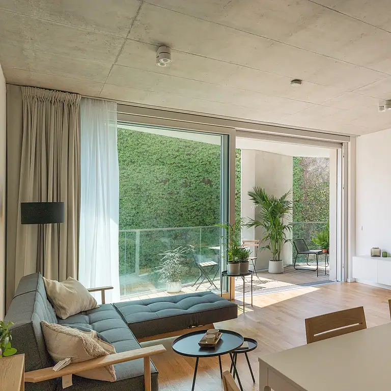 Wohnbereich im Garden Loft 80 mit bodentiefen Fenstern, Echtholzparkett und moderner Einrichtung