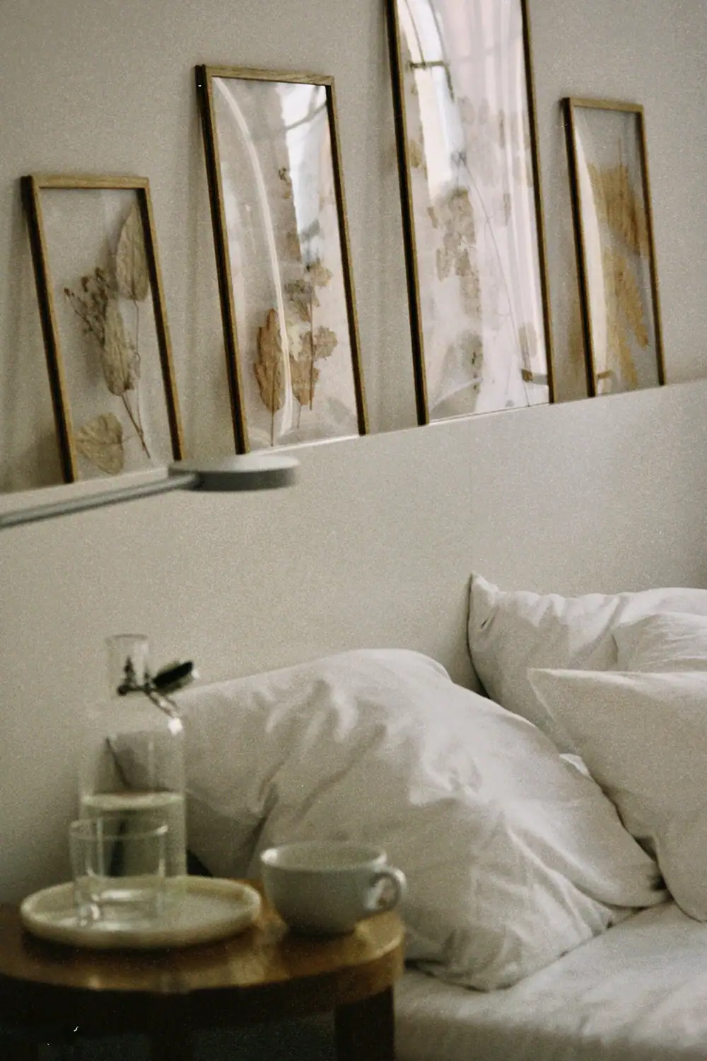 Schlafzimmer mit weißen Bettwäsche und Wandkunst in goldenen Rahmen.