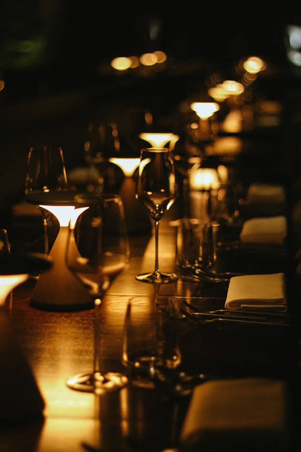 Stimmungsvolle Tafel mit Kerzen, Gläsern und Besteck bei Abenddämmerung.