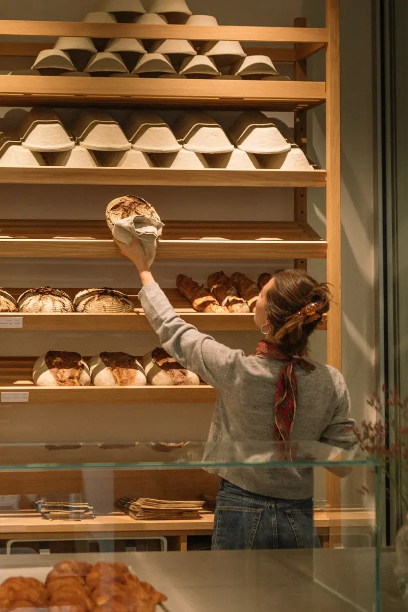 Frau wählt frisches Brot in Bäckerei Wilmina aus.